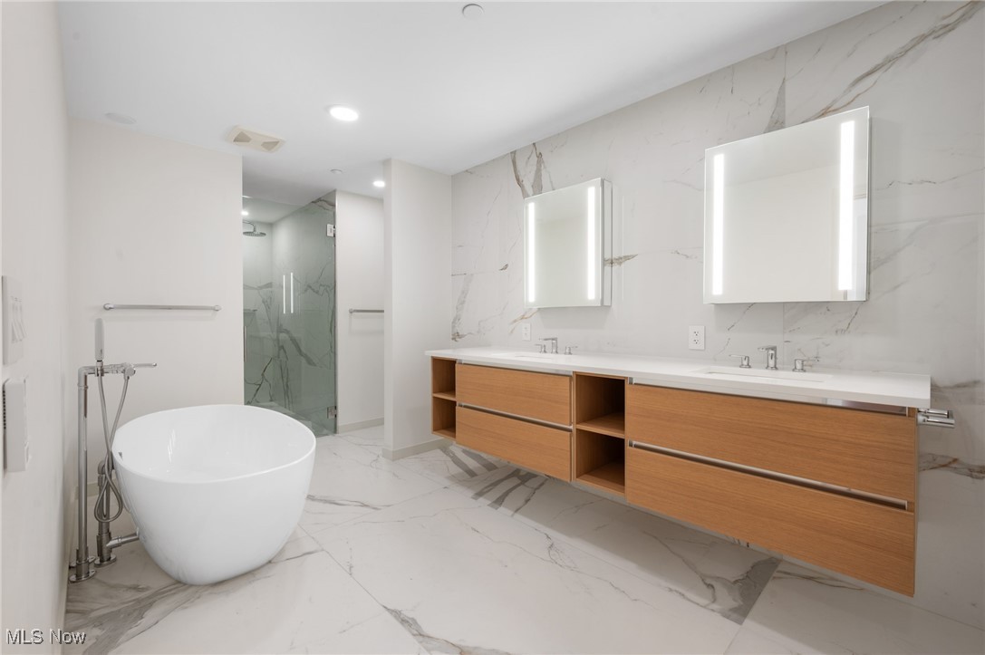 22700 Lake Road, Unit 306 Rocky River, OH 44116 - Photo 16 of 28 Bathroom featuring stone wall, double vanity, a soaking tub, a marble finish shower, and recessed lighting