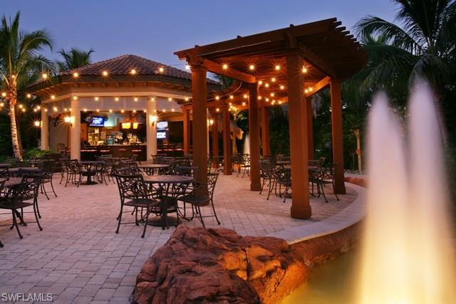 6189 Bunker Place Naples, FL 34113 - Photo 25 of 25 a view of a patio with dining table and chairs under an umbrella with palm trees