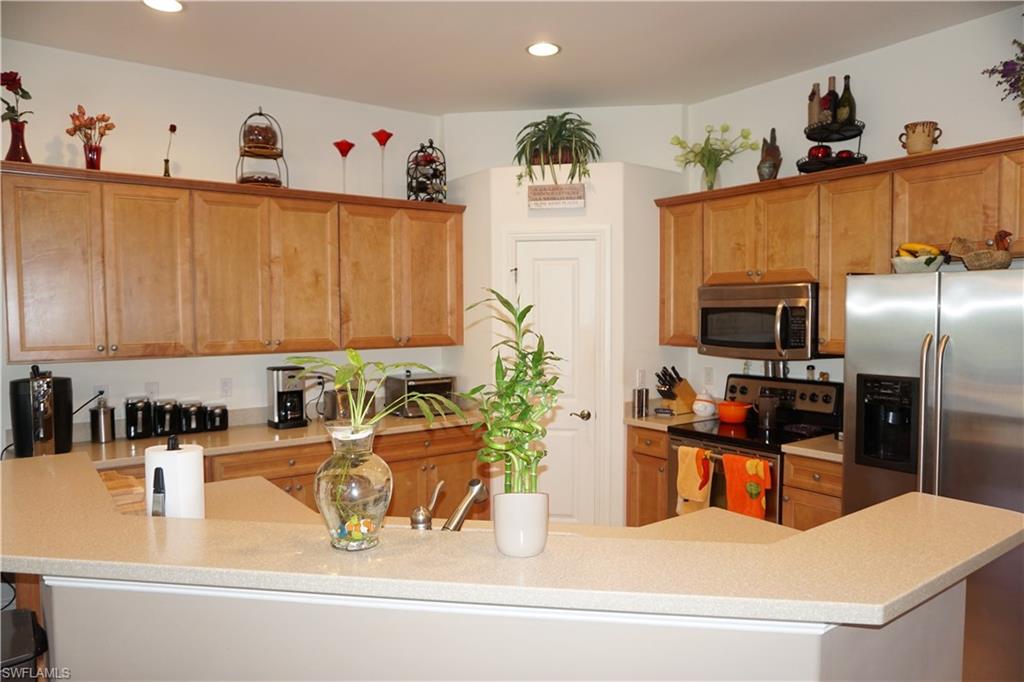 6189 Bunker Place Naples, FL 34113 - Photo 7 of 25 a kitchen with kitchen island granite countertop a sink a counter top space appliances and cabinets