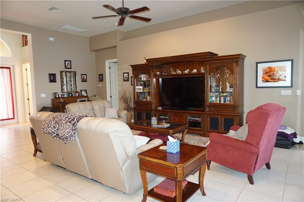 6189 Bunker Place Naples, FL 34113 - Photo 9 of 25 a living room with furniture a flat screen tv and a fireplace