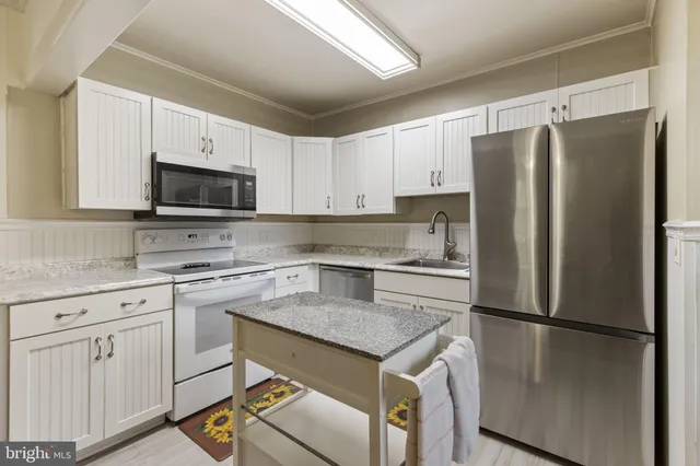 a kitchen with a refrigerator a microwave a sink and cabinets