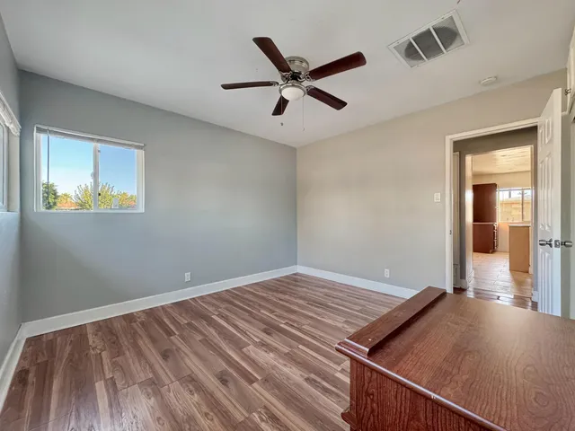a view of an empty room with a window and wooden floor