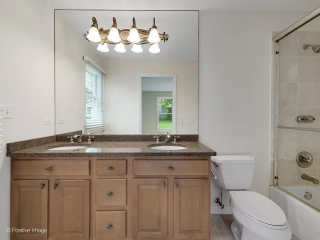a bathroom with a granite countertop sink a toilet and a mirror