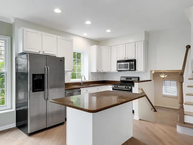 a kitchen with granite countertop a refrigerator a sink a stove a microwave and island