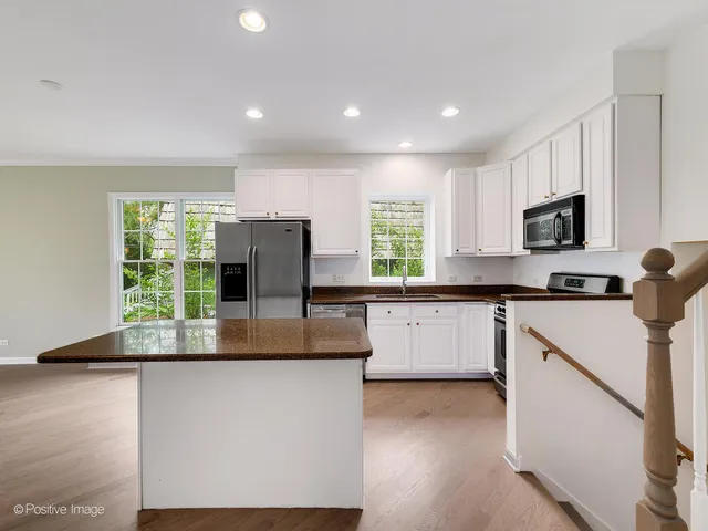 a kitchen with kitchen island granite countertop white cabinets and refrigerator