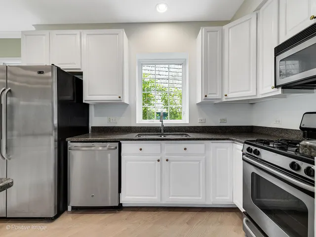 a kitchen with granite countertop white cabinets and stainless steel appliances