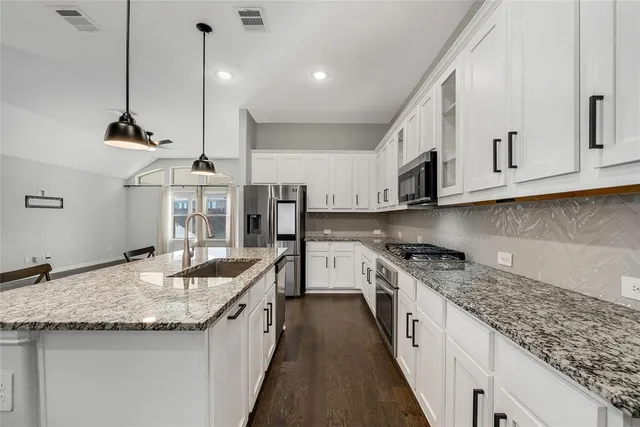 a kitchen with stainless steel appliances granite countertop a sink a stove and a wooden floors