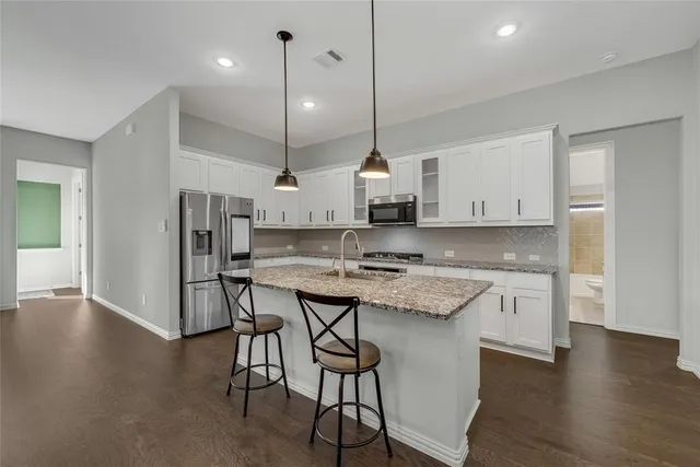 a kitchen with stainless steel appliances kitchen island a wooden floor and white cabinets