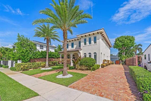 a front view of a house with garden and trees