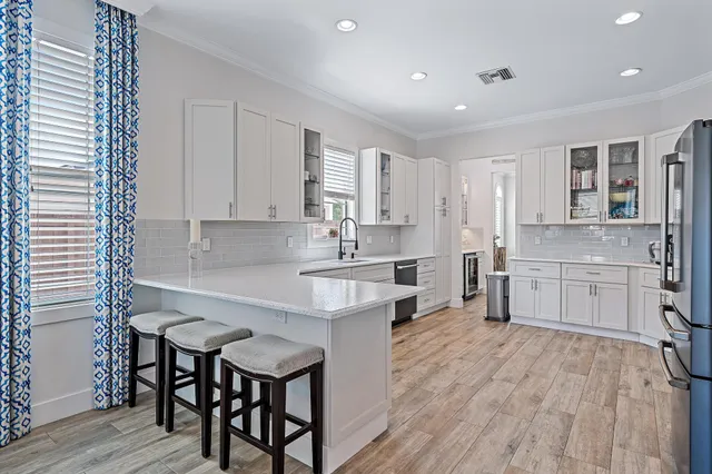 a kitchen with stainless steel appliances granite countertop a sink dishwasher stove and white cabinets with wooden floor