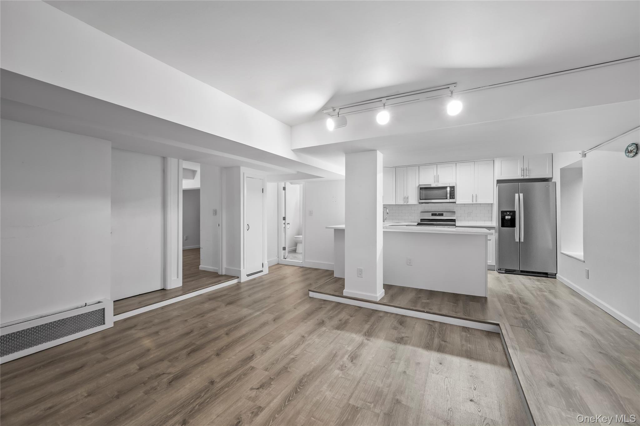 1440 Boston Post Road, Unit 8K Larchmont, NY 10538 - Photo 8 of 20 Kitchen featuring stainless steel appliances, white cabinets, wood finished floors, and backsplash