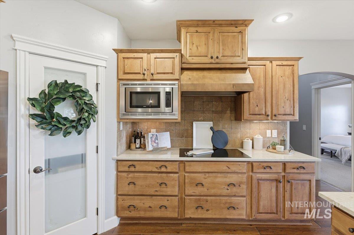 8982 New Castle Drive Middleton, ID 83644 - Photo 14 of 48 Kitchen featuring wall chimney range hood, stainless steel microwave, tasteful backsplash, light stone countertops, and recessed lighting