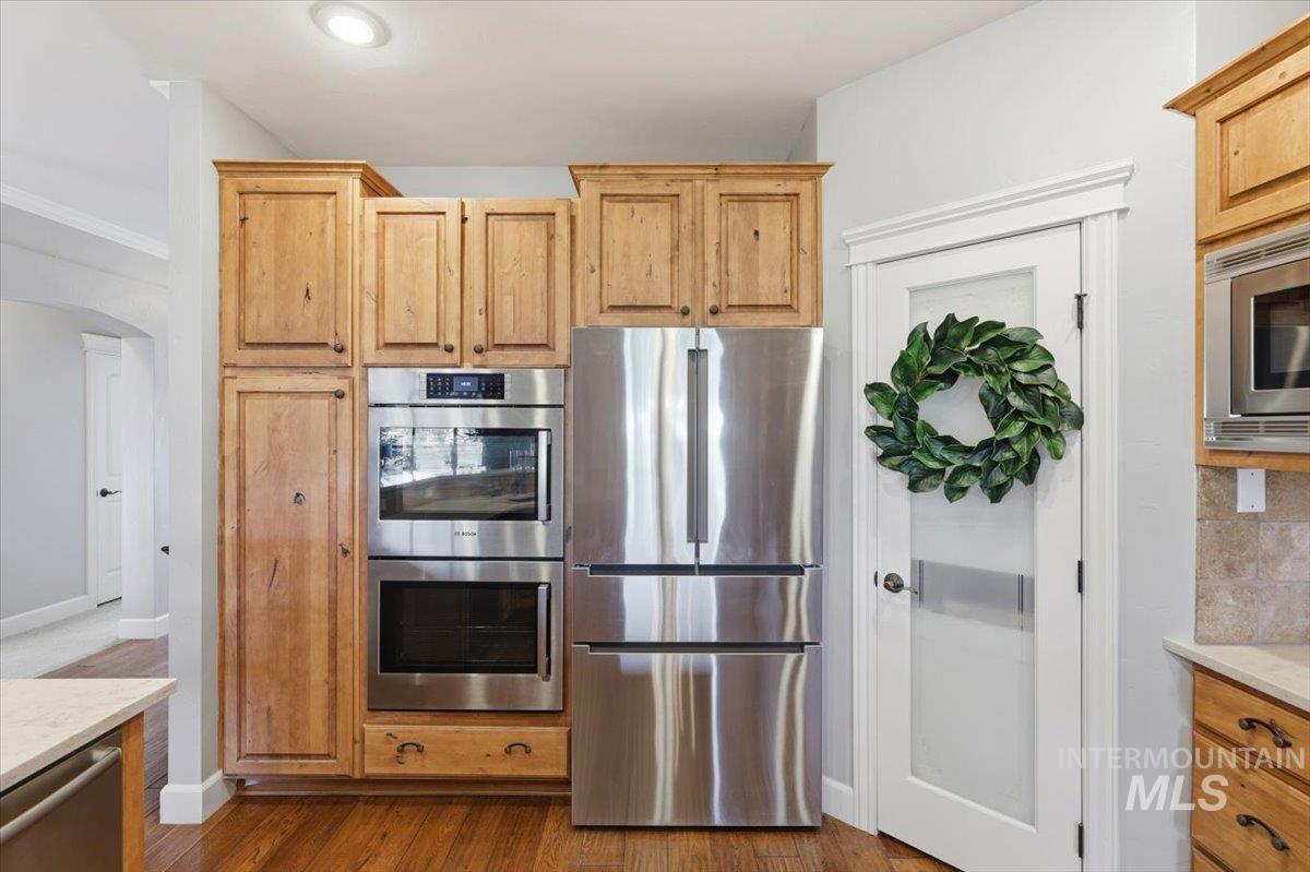 8982 New Castle Drive Middleton, ID 83644 - Photo 15 of 48 Kitchen featuring stainless steel appliances, light stone countertops, dark wood finished floors, and arched walkways