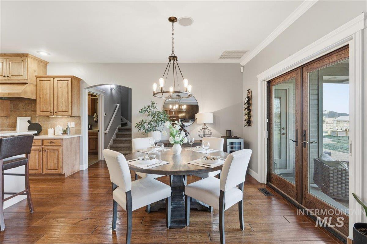 8982 New Castle Drive Middleton, ID 83644 - Photo 19 of 48 Dining room featuring stairway, arched walkways, dark wood-type flooring, and a chandelier