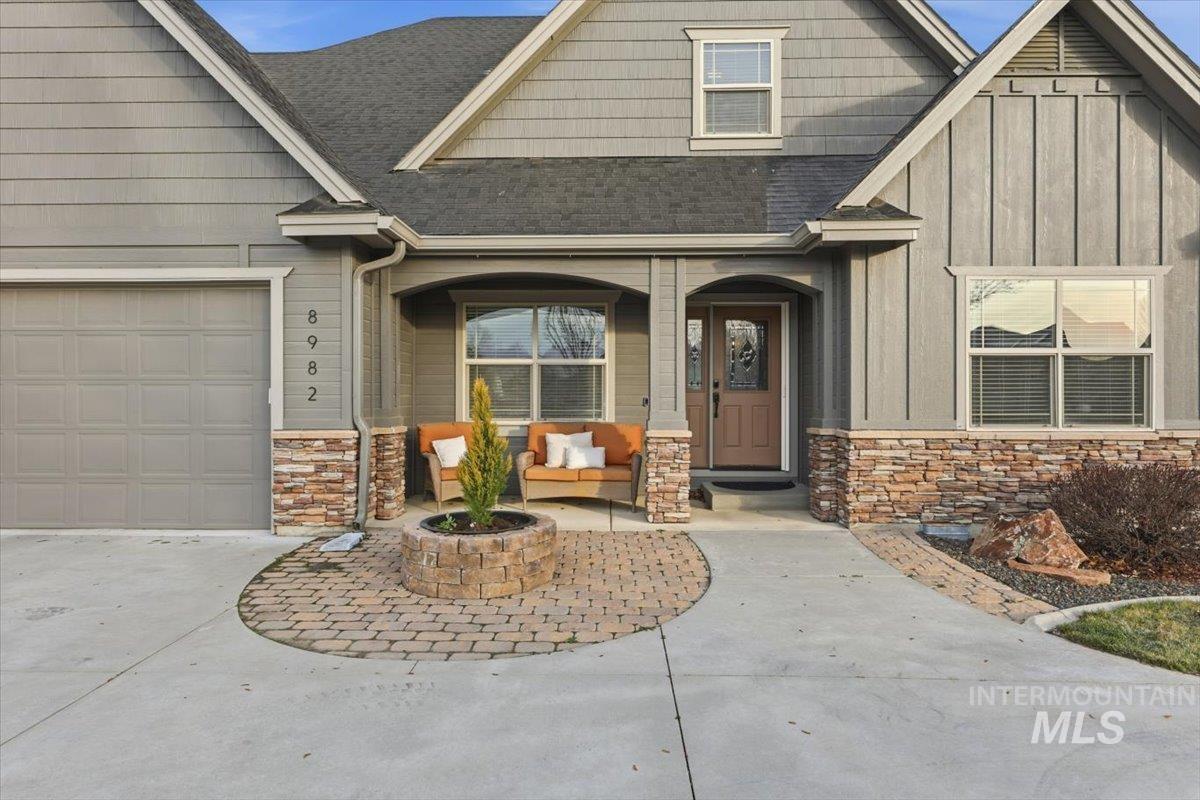 8982 New Castle Drive Middleton, ID 83644 - Photo 5 of 48 View of front of home featuring stone siding, a porch, a shingled roof, and driveway