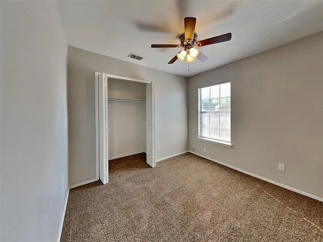 an empty room with a ceiling fan and a window