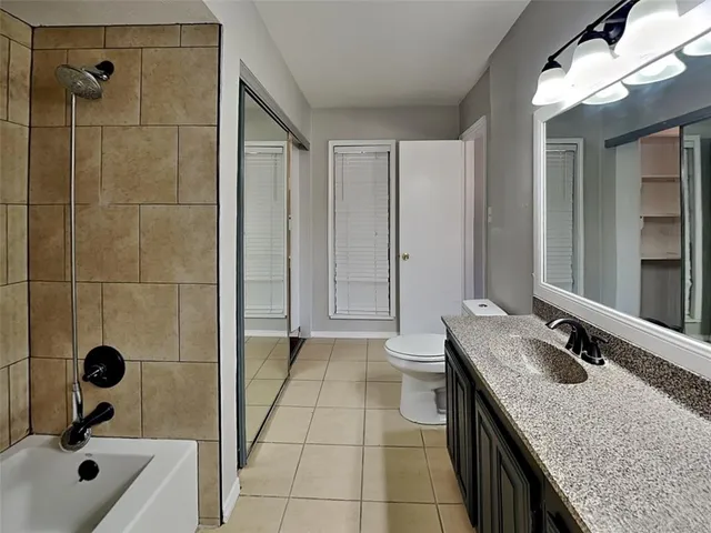 a bathroom with a granite countertop sink a toilet and shower