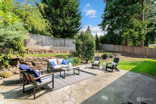 a view of backyard with table and chairs and a large tree