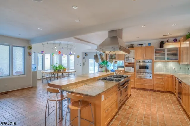 a kitchen with stainless steel appliances granite countertop a kitchen island a stove a sink dishwasher and cabinets with wooden floor