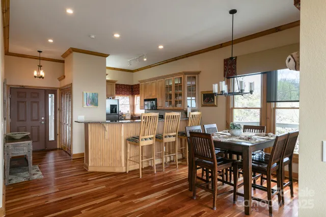 a dining room with stainless steel appliances kitchen island granite countertop a table chairs and a refrigerator
