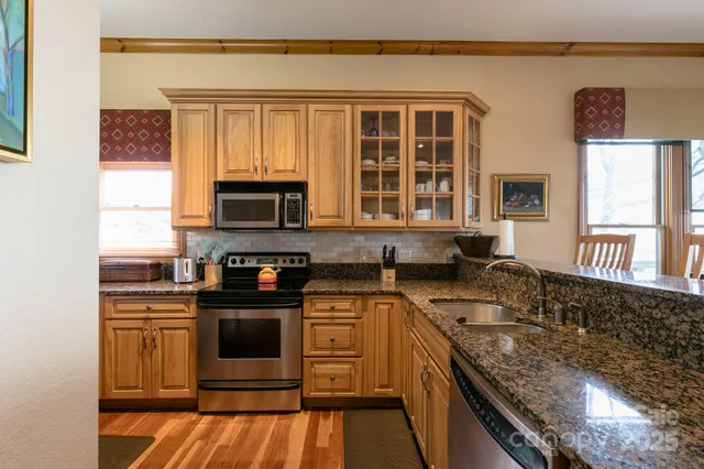 a kitchen with stainless steel appliances granite countertop a stove a sink and a microwave