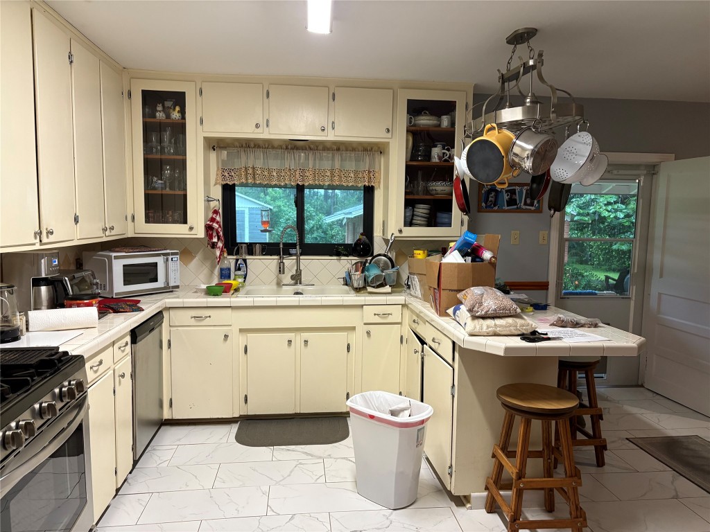5152 Richardson Road East Livingston, TX 77351 - Photo 7 of 13 a kitchen with a sink dishwasher a stove a microwave oven with a dining table and chairs