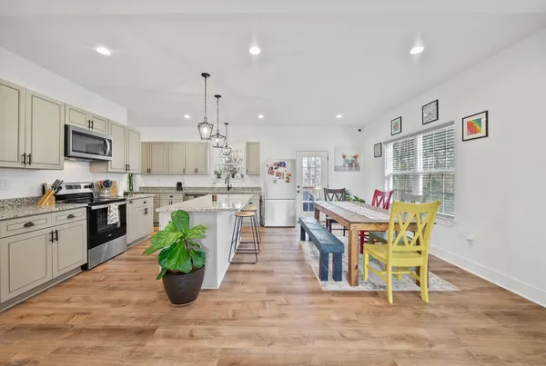 a living room with dining table and a refrigerator
