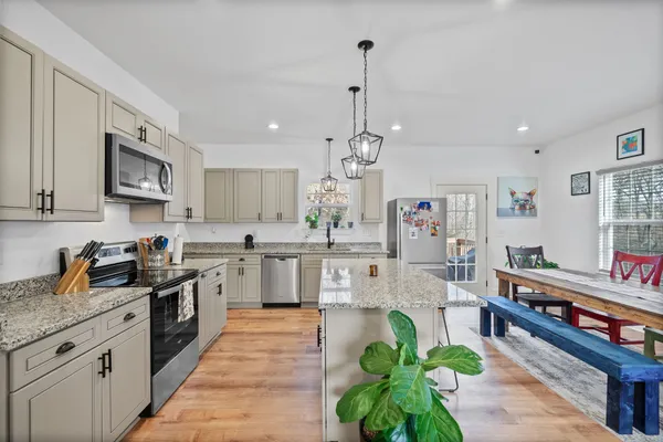 a kitchen with granite countertop a sink stainless steel appliances and white cabinets