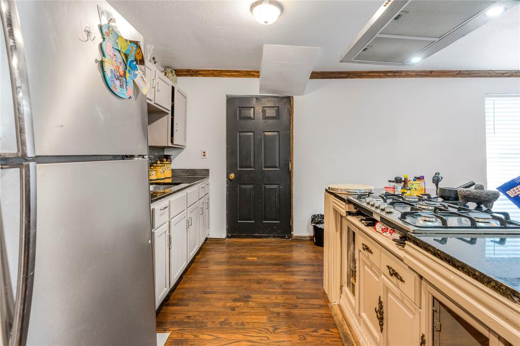 548 Elston Drive Dallas, TX 75232 - Photo 6 of 18 Kitchen featuring appliances with stainless steel finishes, crown molding, dark wood-style flooring, extractor fan, and dark stone counters