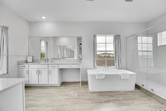 a spacious bathroom with a double vanity sink large mirror and a bathtub