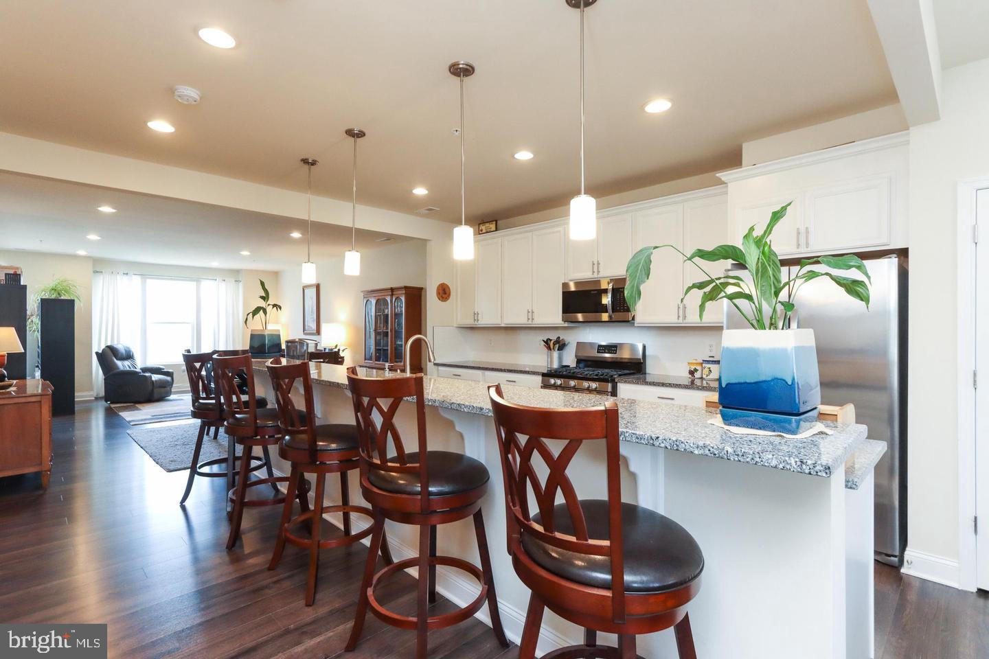 7146 Proclamation Place Frederick, MD 21703 - Photo 4 of 26 a kitchen with stainless steel appliances kitchen island granite countertop a dining table chairs and white cabinets