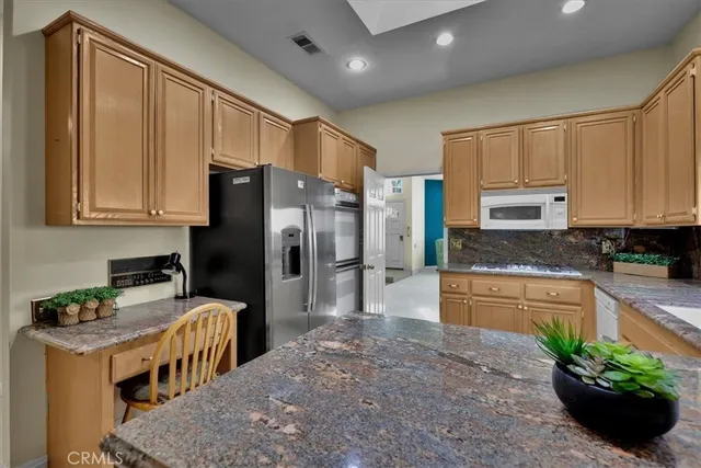 a kitchen with granite countertop a stove a sink and a refrigerator