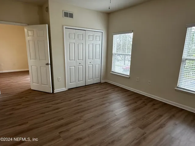 an empty room with wooden floor and windows
