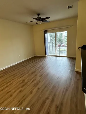 a view of an empty room with a window and wooden floor