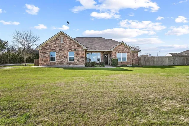 a view of a house next to a big yard with large trees
