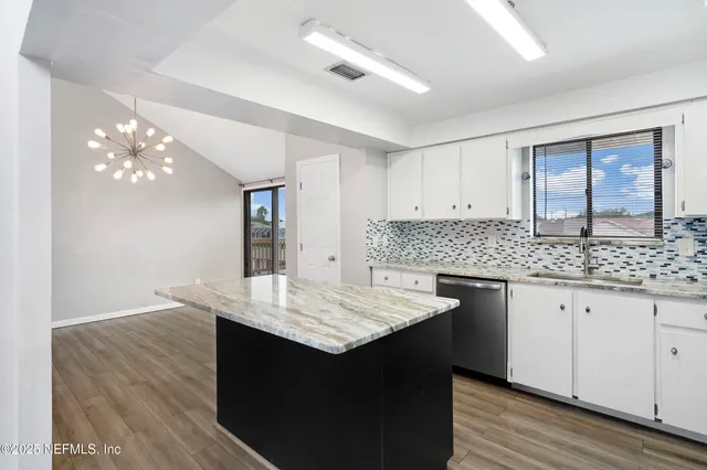 a kitchen with granite countertop cabinets a sink dishwasher and a stove with wooden floor