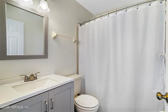 a bathroom with a sink a toilet and shower curtain