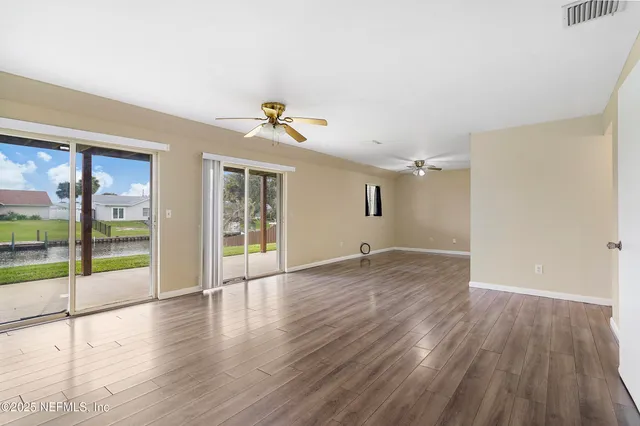 a view of empty room with wooden floor and fan