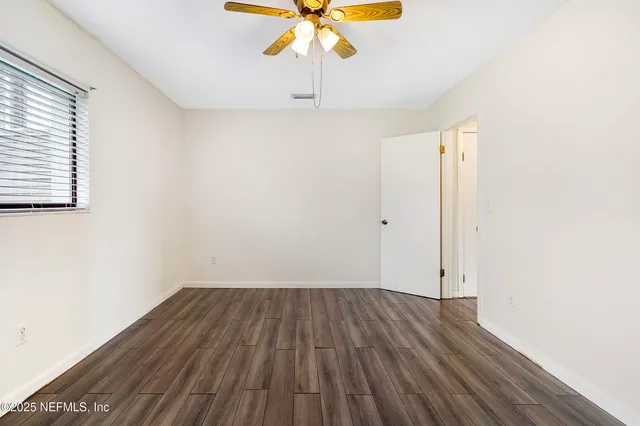 a view of a room with wooden floor and a ceiling fan