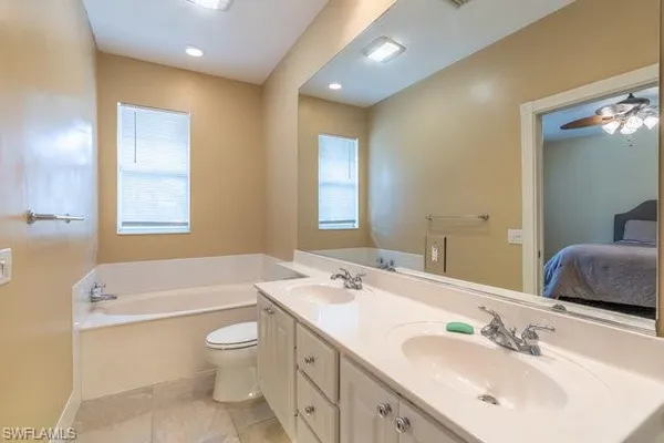 a bathroom with a toilet a sink a tub and mirror
