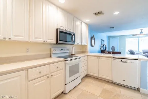 a kitchen with white cabinets and white appliances