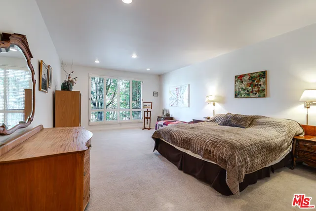 a bedroom with a bed a dresser next to a window