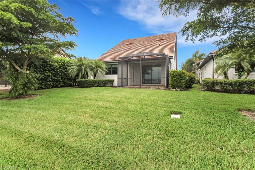 20281 Corkscrew Shores Boulevard Estero, FL 33928 - Photo 27 of 40 a view of a white house with a big yard and potted plants and large trees