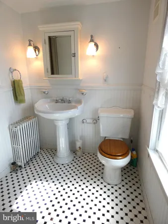 a bathroom with a sink toilet a mirror and window