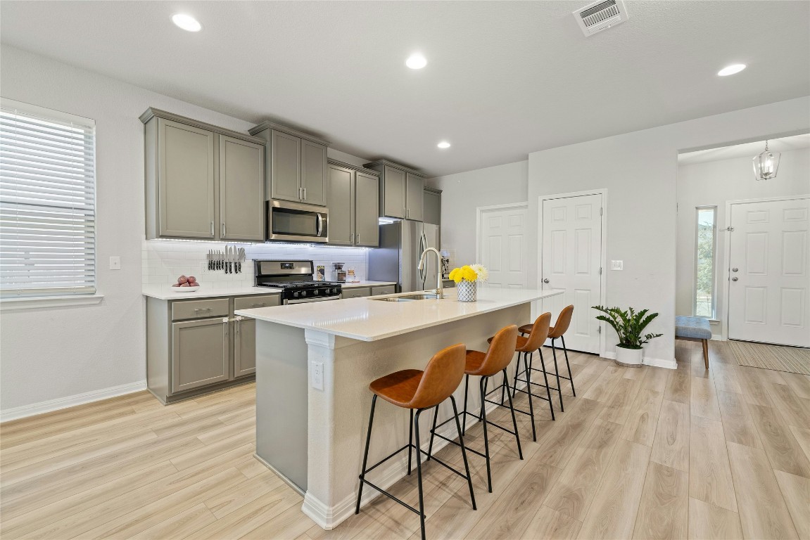 436 Staunton Drive Leander, TX 78641 - Photo 11 of 39 Kitchen featuring visible vents, an island with sink, appliances with stainless steel finishes, a kitchen breakfast bar, and a sink