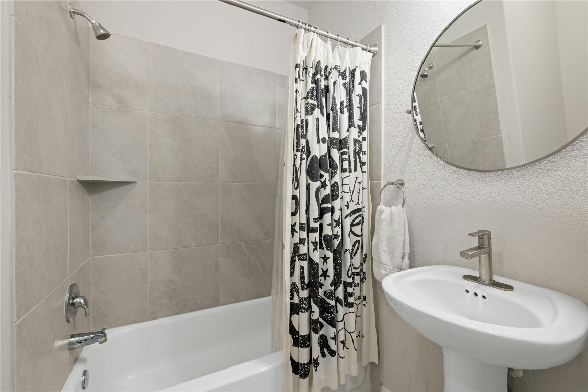 436 Staunton Drive Leander, TX 78641 - Photo 20 of 39 Bathroom with a textured wall, a sink, and shower / bathtub combination with curtain