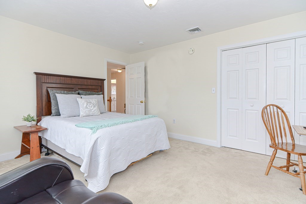 237 Pleasant Street, Unit 237 Norwood, MA 02062 - Photo 19 of 40 a bedroom with a bed and chair
