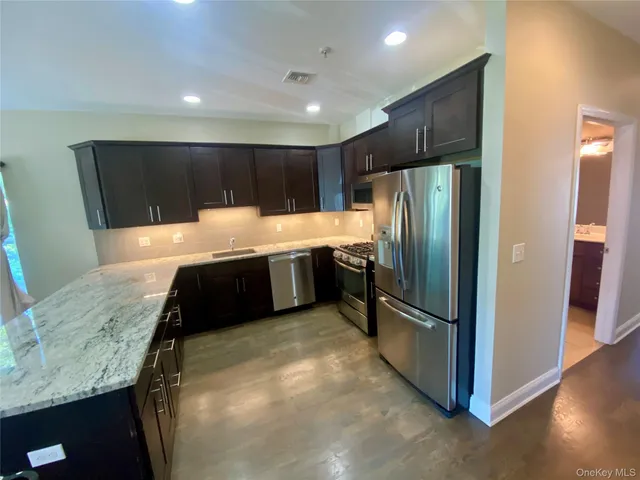 a kitchen with stainless steel appliances granite countertop a refrigerator a sink and a stove