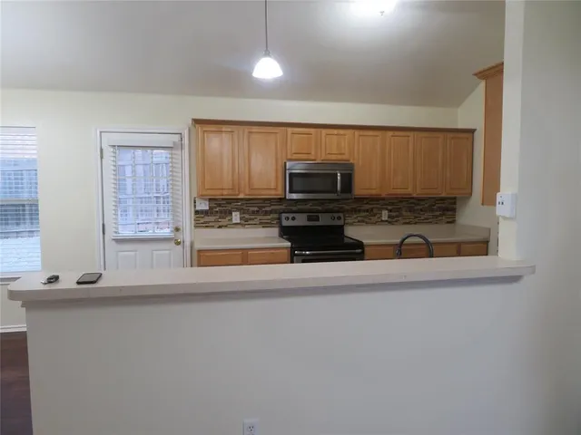 a kitchen with stainless steel appliances a stove a microwave and white cabinets