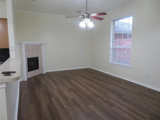 a view of an empty room with wooden floor fireplace and a window